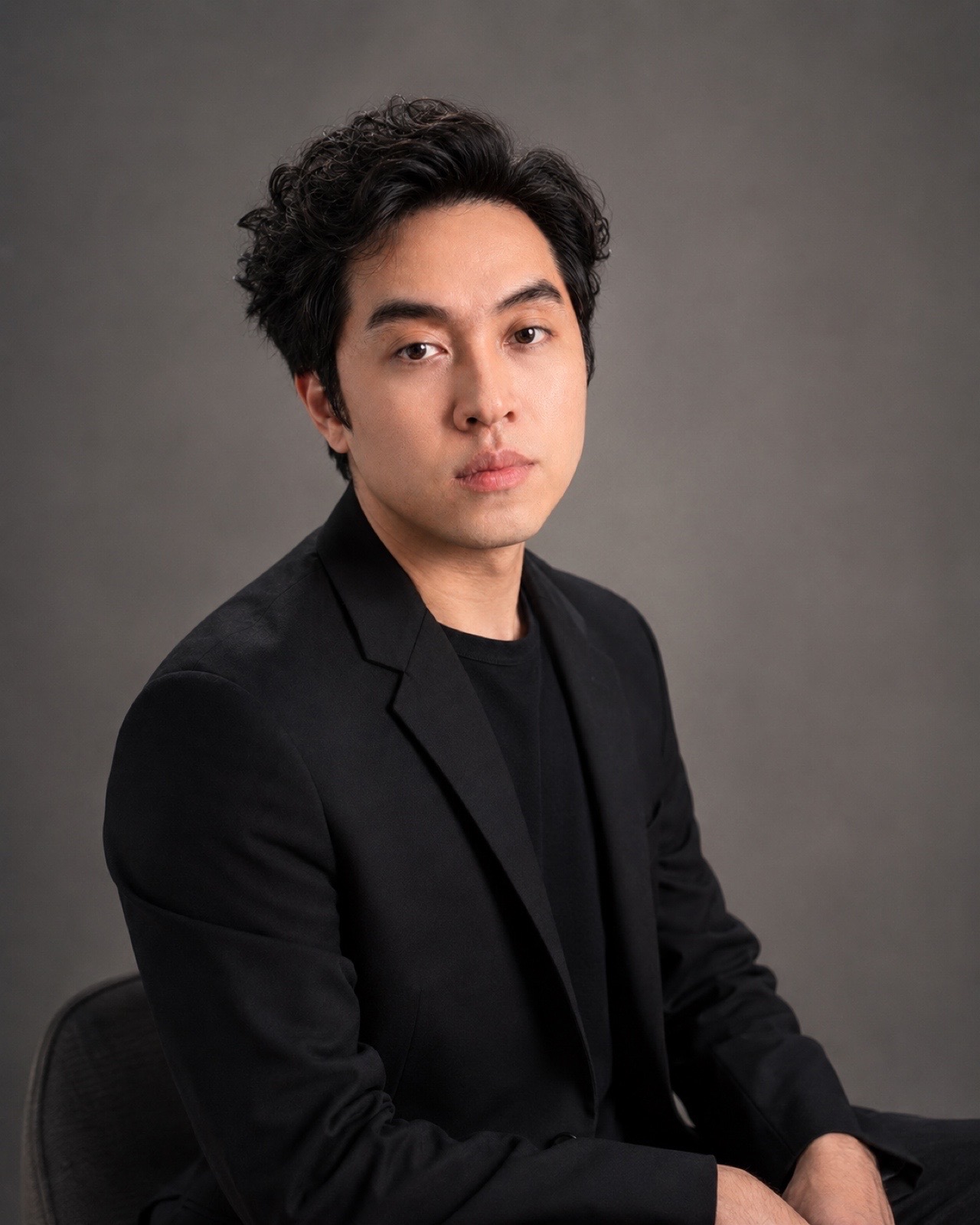Portrait of Ryan V. Visith wearing a black blazer against a neutral studio background.
